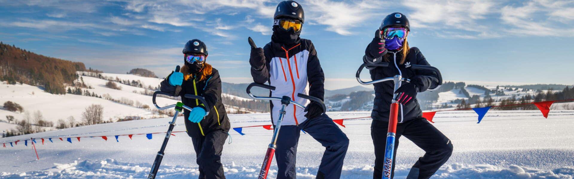 Widok na 3 zadowolone osoby w strojach narciarskich trzymające Skki Trikki do jazdy.