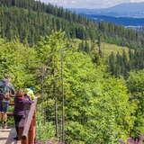 Turyści podziwiający widoki i robiący zdjęcia Nn tarasie przy schronisku na Hali Krupowej z widokiem na góry